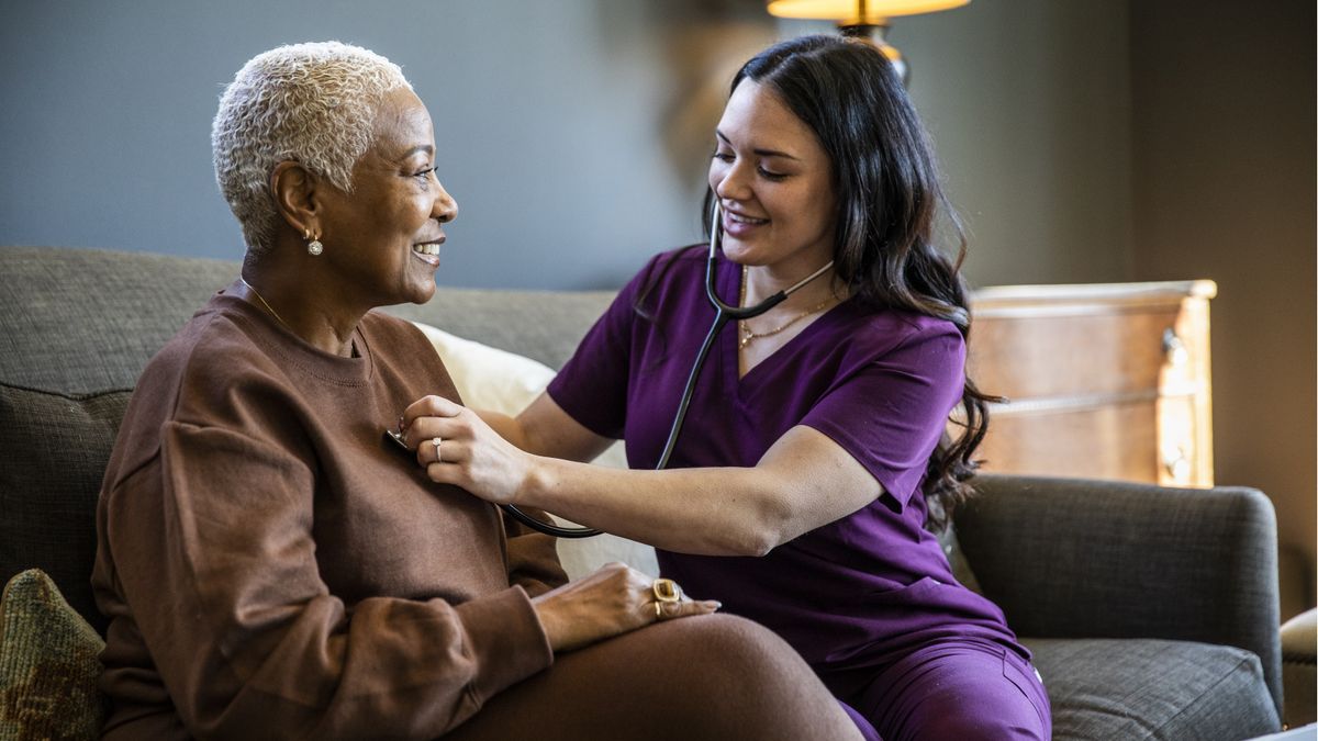 Nurse checking senior woman’s vital signs in her home