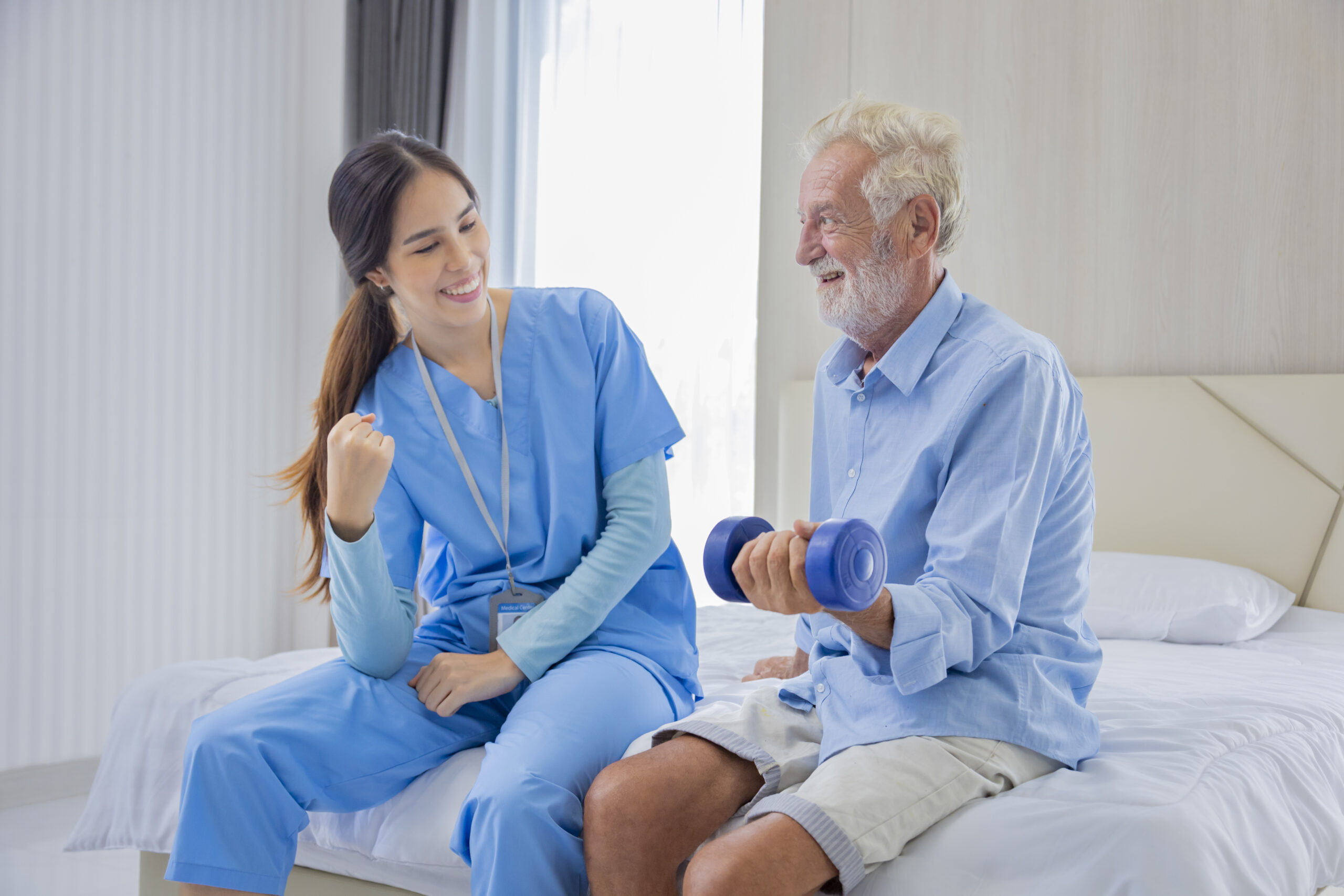 Hospice nurse is helping Caucasian man in bed to exercising musc