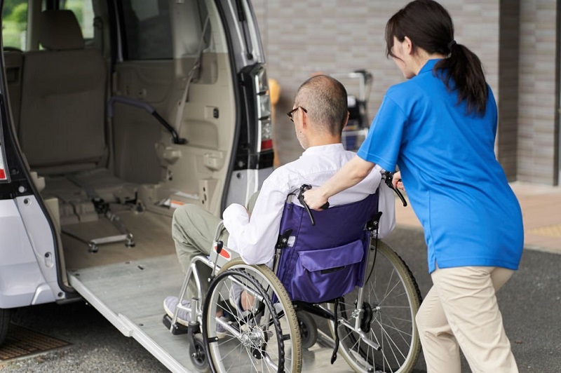 A caregiver who puts an elderly person in a long-term care taxi A caregiver who puts an elderly person in a long-term care taxi
