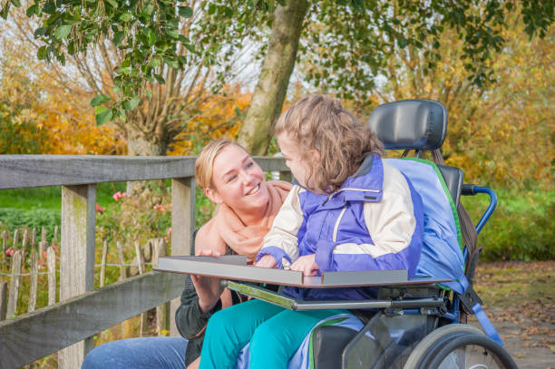 A disabled child in a wheelchair being cared for by a voluntary care worker A disabled child in a wheelchair being cared for by a voluntary care worker